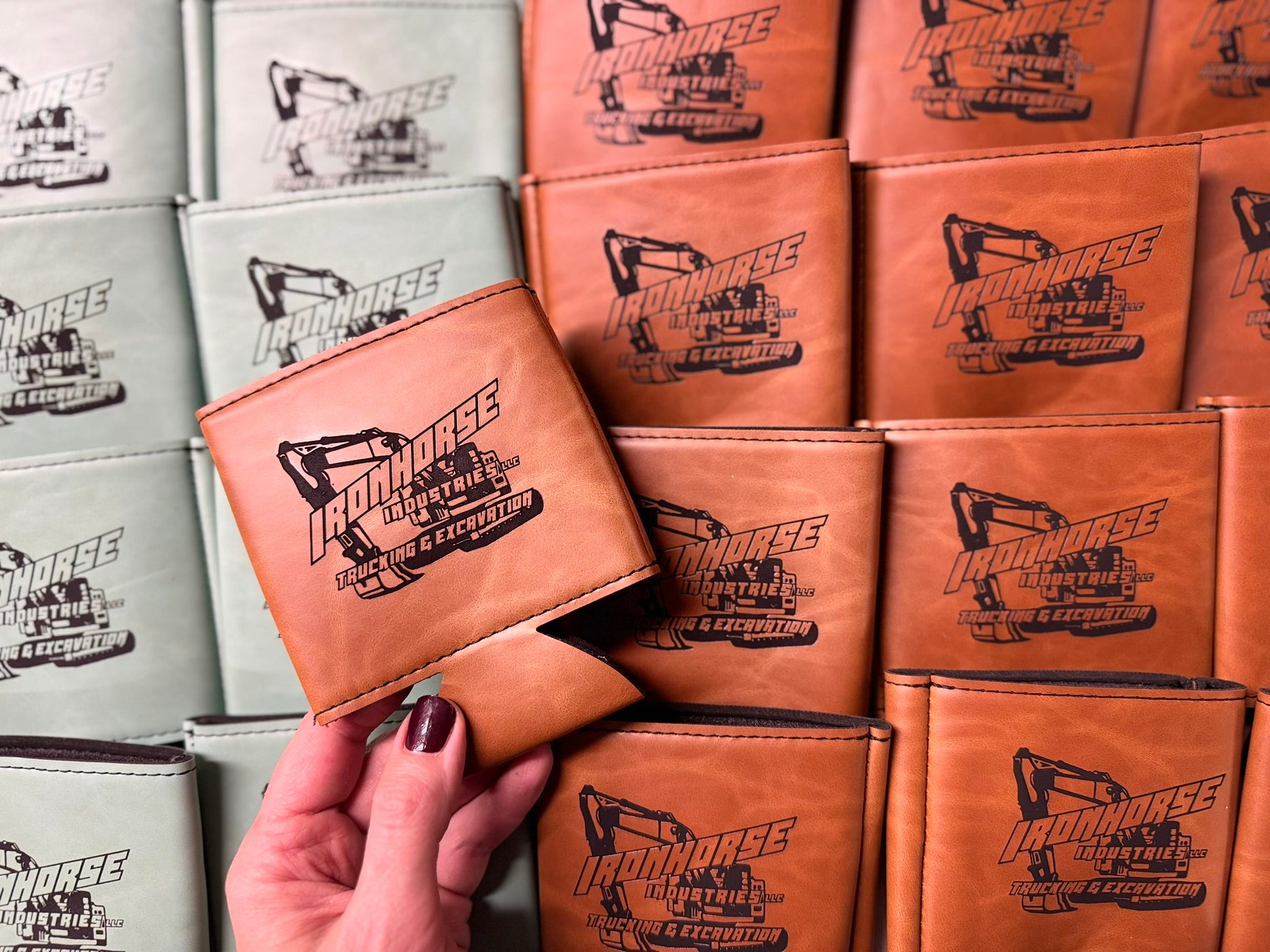 leatherette can dusters with a brand logo engraved on them, held by a hand.