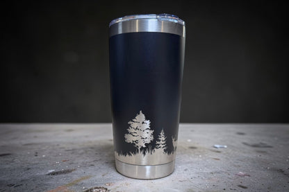 Black tumbler with tree design on a dark surface